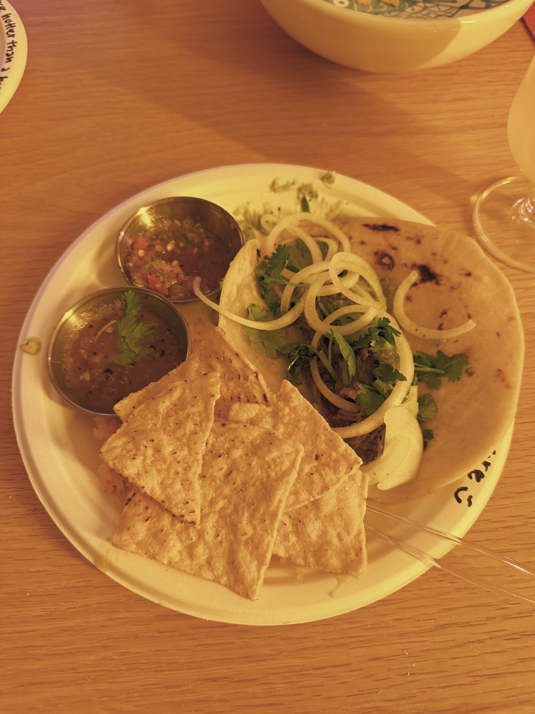 A plated taco with salsas and chips